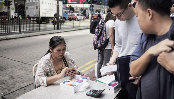 An unauthorized reseller, left, negotiates with a shopper to buy his newly purchased Apple Inc. iPhone X in the Mong Kok district of Hong Kong, China, on Friday, Nov. 3, 2017. It's only†Day One, but the gray market trade in Apple's new iPhone is already in full swing in Hong Kong. Photographer: Justin Chin/Bloomberg