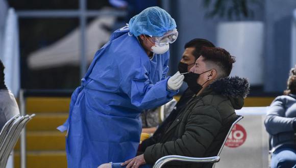 Un trabajador de la salud toma muestras para evaluar a las personas por la enfermedad del coronavirus COVID-19, en la explanada del Hospital General Carlos MacGregor del IMSS en la Ciudad de México. (Foto: Pedro PARDO / AFP).