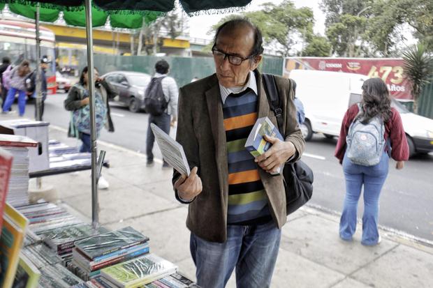 Alberto revisando los libros en el puesto de doña Erika, frente a la Puerta 2 de San Marcos. Foto: Julio Reaño.