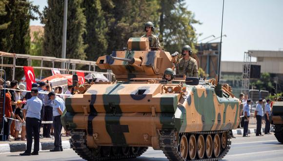Soldados turcos aparecen montados en un vehículo de combate de infantería, durante una ceremonia oficial que conmemora la invasión de Chipre por parte de Turquía en 1974. (BIROL BEBEK / AFP).