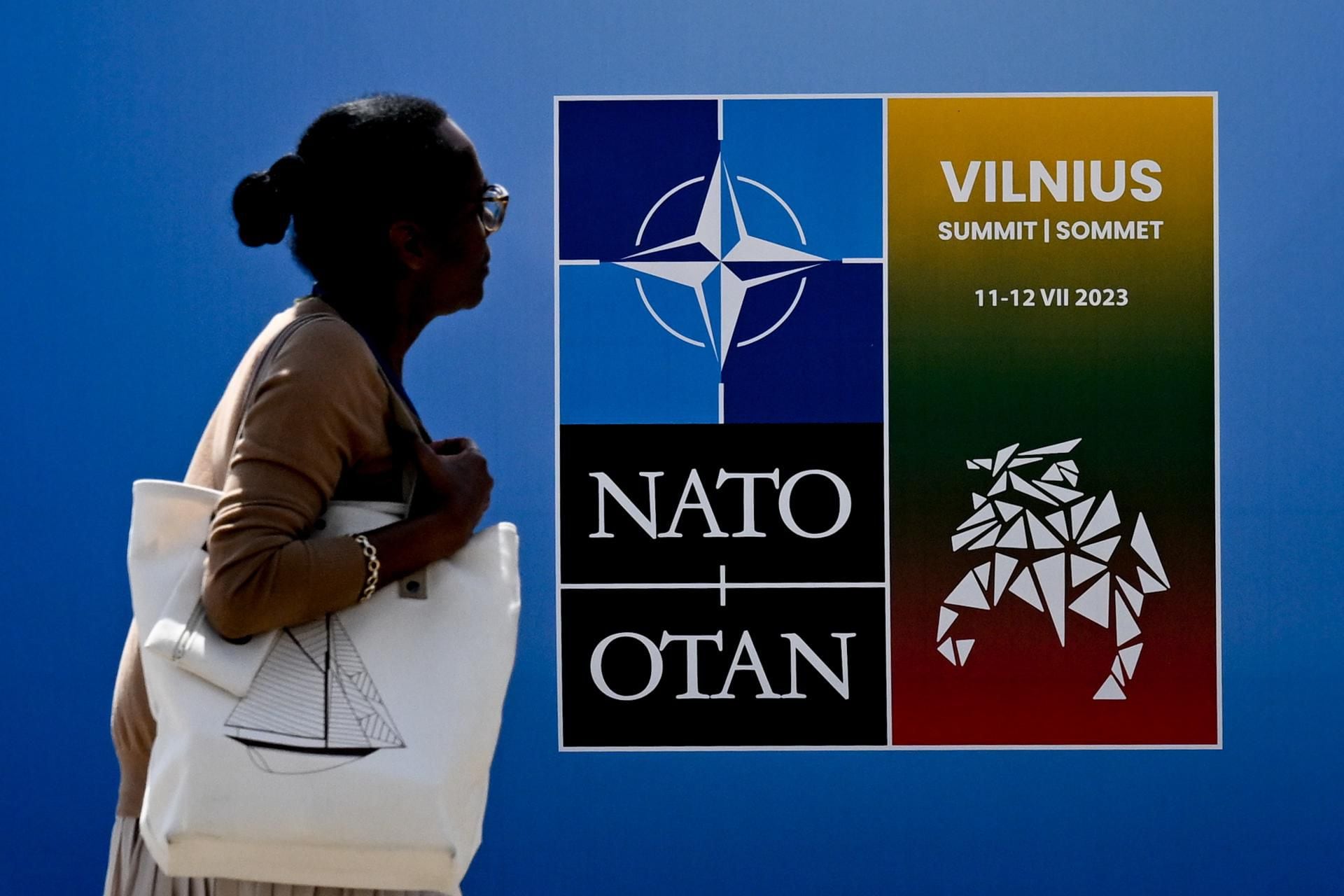 A woman walks past a NATO poster at the NATO summit venue in Vilnius, Lithuania, on July 9, 2023. (EFE/EPA/FILIP SINGER).