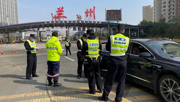 La policía trabaja en un puesto de control a la entrada de una autopista en la ciudad de Lanzhou, donde se requieren los resultados de la prueba del coronavirus para entrar y salir. (STR / AFP).