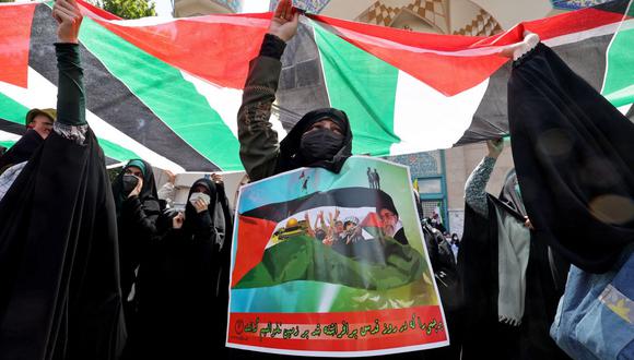Manifestantes iraníes ondean banderas nacionales palestinas durante una protesta en Teherán para condenar la campaña aérea israelí en curso en Gaza. (Foto de ATTA KENARE / AFP).