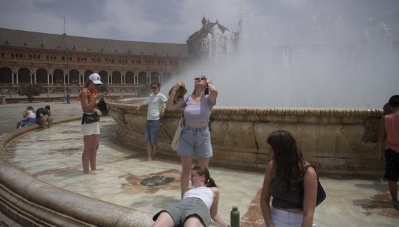 La gente se refresca con el agua de una fuente durante la ola de calor en Sevilla el 12 de julio de 2022. (Foto:  JORGE GUERRERO / AFP)