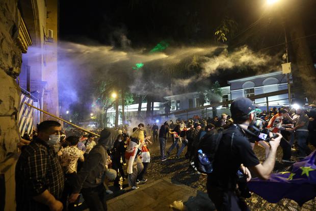 Policía utiliza gases lacrimógenos y un cañón de agua mientras los manifestantes intentan bloquear la entrada lateral del parlamento georgiano durante una manifestación, en Tiflis, el 1 de mayo de 2024. (Foto de Giorgi ARJEVANIDZE / AFP)