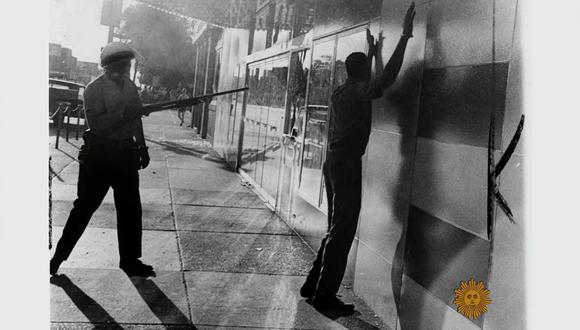 Fotografía que muestra a un policía apuntando a un ciudadano afroamericano, durante las revueltas de 1967 en Detroit. Pantallazo extraído de You Tube. (You Tube, CBS Sunday Morning)