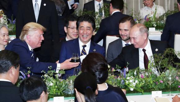 En la imagen se puede observar al presidente estadounidense Donald Trump y al mandatario ruso Vladimir Putin brindando. El primero con una copa de vidrio y el segundo con un termo. (Reuters)
