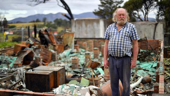 Esta imagen, tomada el pasado de mayo de 2020, muestra a Wayne Keft, de 66 años, parado frente a las ruinas de su casa destruidas durante los incendios forestales cerca de Cobargo, una ciudad en la costa sur del estado de Nueva Gales del Sur. Las víctimas de los catastróficos incendios forestales de Australia todavía viven en tiendas de campaña, garajes y refugios improvisados expuestos a la pandemia del COVID-19. (Saeed KHAN / AFP).
