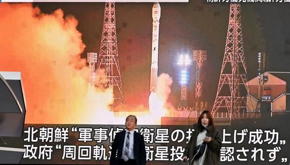 Peatones pasan junto a una pantalla que muestra el lanzamiento del satélite de reconocimiento de Corea del Norte 'Malligyong-1', en el distrito de Akihabara de Tokio el 22 de noviembre de 2023. (Foto de Kazuhiro NOGI / AFP)