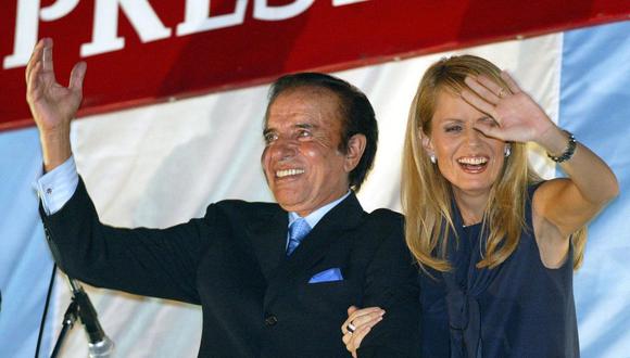 En esta foto de archivo tomada el 26 de abril de 2003, el candidato presidencial argentino Carlos Menem y su esposa Cecilia Bolocco saludan el balcón de un hotel en Buenos Aires. (Foto de DANIEL GARCIA / AFP).