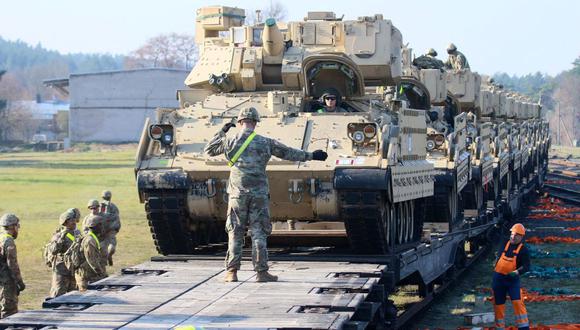 En esta imagen del 21 de octubre de 2019, miembros del Ejército de Estados Unidos descargan equipo de combate pesado, incluidos tanques Abrams y vehículos de combate Bradley, cerca de la base militar de Pabrade en Lituania. (PETRAS MALUKAS / AFP).