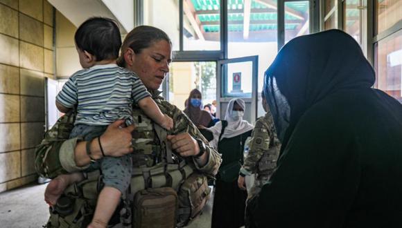 Un oficial médico asignado a la 82 División Aerotransportada que habla con una mujer afgana y la ayuda con su hijo como parte de la evacuación en curso de no combatientes del personal civil de EE.UU. (Foto: Jillian HIX / US ARMY / AFP).