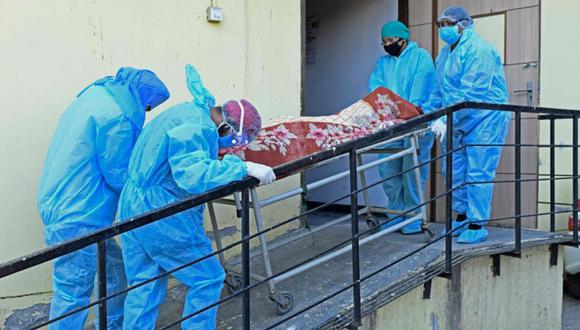Miembros del personal médico con equipo de protección llevan el cadáver de una víctima del coronavirus en un hospital en Amritsar. (Foto: AFP / Narinder NANU).