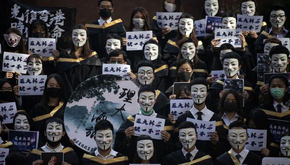 Un grupo de estudiantes de la Universidad Politécnica de Hong Kong usan máscaras de Guy Fawkes, popularizadas por la película 'V For Vendetta', antes de su ceremonia de graduación para conmemorar un mes de la ordenanza que prohíbe el uso de coberturas faciales en protestas. (Archivo / AFP)
