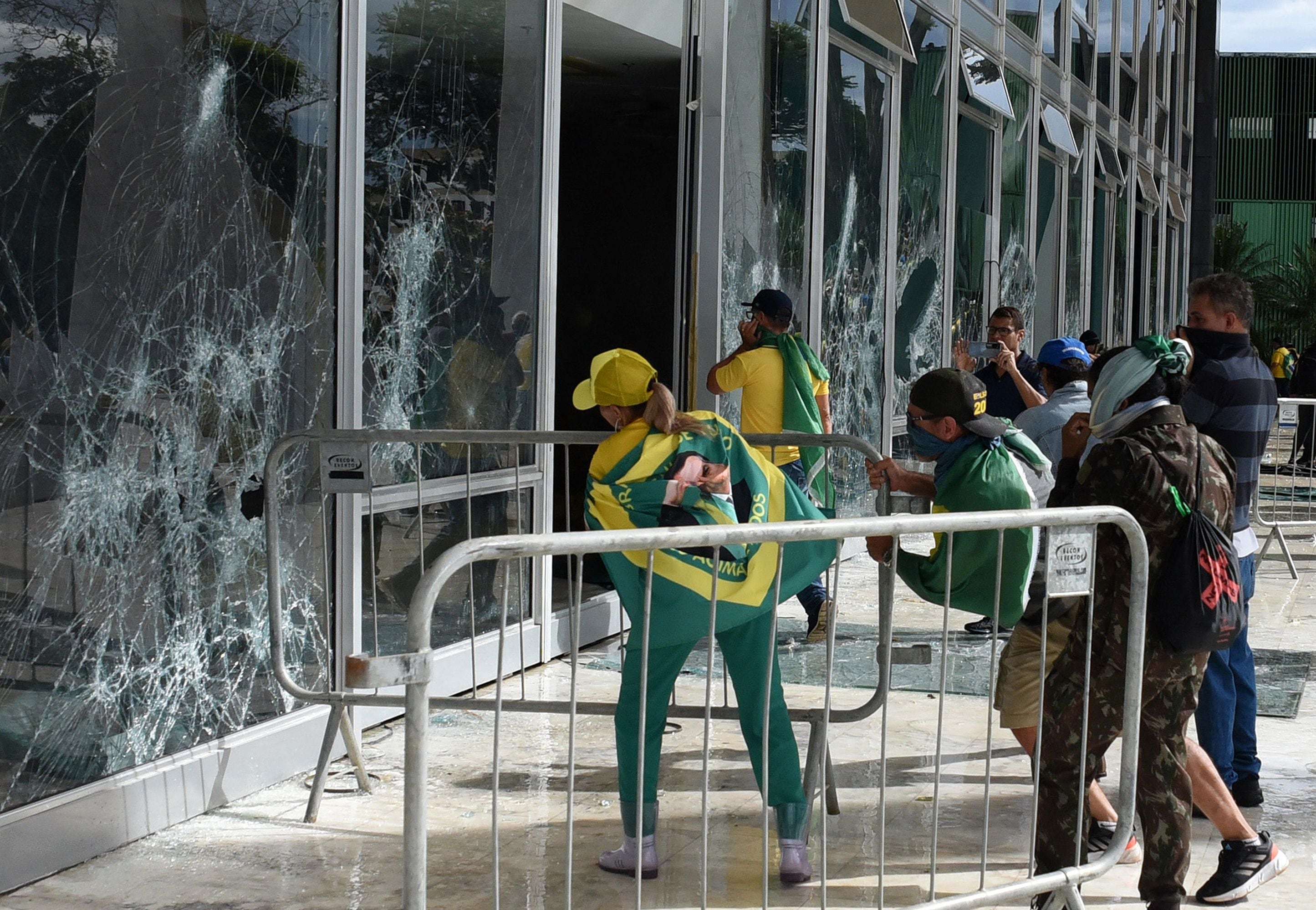 Supporters of former Brazilian president Jair Bolsonaro destroy a window of the Federal Supreme Court in Brasília on January 8, 2023. (Photo Ton MOLINA / AFP).