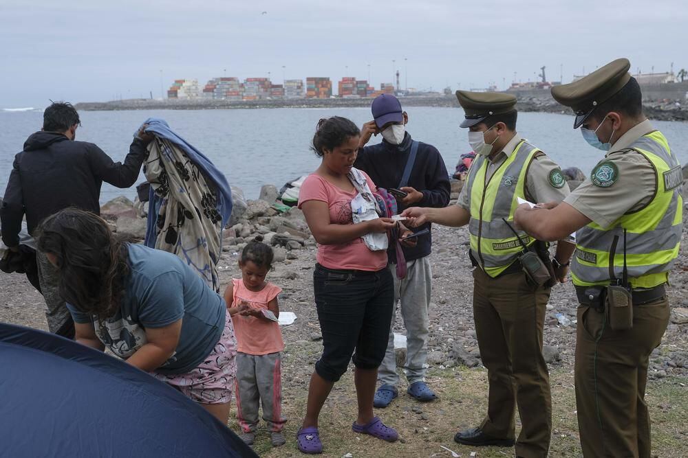 Venezuelan migrant Magdelis Alejos hands over her identification documents to the police, on the seashore where she lives with her family in El Morro, a neighborhood of Iquique, Chile, on Sunday, December 12, 2021. (AP / Matias Delacroix)