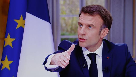 El presidente francés Emmanuel Macron se ve en la pantalla mientras habla durante una entrevista televisiva desde el Palacio del Elíseo, en París, el 22 de marzo de 2023. (Foto de Ludovic MARIN / AFP)