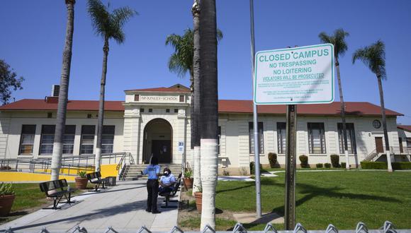 Dos guardias de seguridad hablan en el campus de la Escuela McKinley cerrada, parte del sistema del Distrito Escolar Unificado de Los Ángeles (LAUSD), en Compton, California, justo al sur de Los Ángeles, el 28 de abril de 2020. (Foto de Robyn Beck / AFP )