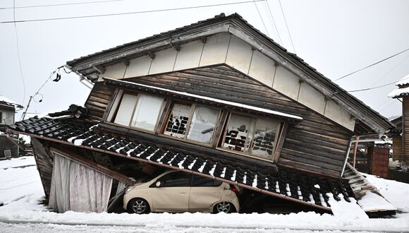 Un automóvil dañado yace debajo de un edificio derrumbado en la ciudad de Shika, prefectura de Ishikawa, Japón, el 8 de enero de 2024. (Foto de Philip FONG / AFP).