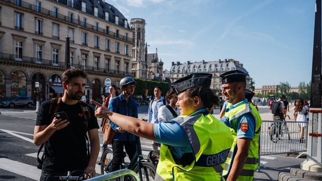 Agentes de la gendarmería francesa controlan los códigos QR y el equipaje de peatones y ciclistas en un puesto de control alrededor del Museo del Louvre de París días antes de la inauguración de los Juegos Olímpicos 2024.