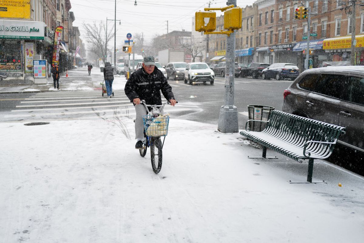 Un hombre anda en bicicleta por una acera mientras cae nieve en el vecindario de Fort Hamilton en el distrito de Brooklyn de la ciudad de Nueva York el 6 de enero de 2025 (Foto: Charly Triballeau / AFP)
