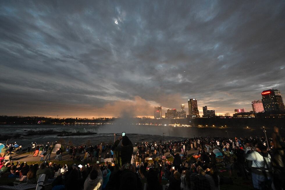 El cielo se oscurece mientras la gente observa durante la totalidad del eclipse solar total en América del Norte, en el Parque Estatal de las Cataratas del Niágara en Niágara Falls, Nueva York, el 8 de abril de 2024. (Foto de ANGELA WEISS / AFP)