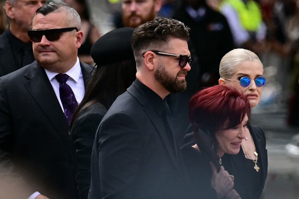 La familia de Ozzy Osbourne (de izquierda a derecha): su hijo Louis, su hija Aimee, su hijo Jack, su viuda Sharon y su hija Kelly, llegan para colocar flores en la banca del Black Sabbath Bridge, en Broad Street, durante el cortejo fúnebre de Ozzy Osbourne, el fallecido vocalista de Black Sabbath, en Birmingham, centro de Inglaterra, el 30 de julio de 2025 | Foto: AFP