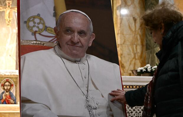 Un devoto toca el retrato del difunto papa Francisco durante una misa en homenaje tras su fallecimiento, celebrada en la iglesia argentina de Santa María la Mayor de Roma, el 21 de abril de 2025. Foto: Filippo MONTEFORTE / AFP