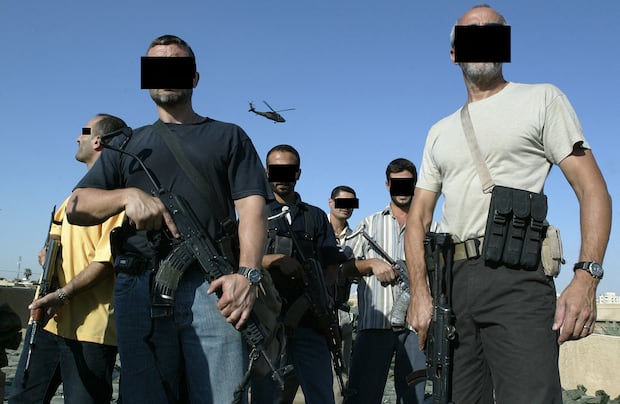 Mercenarios iraquíes y extranjeros miembros de Blackwater están en la azotea de una casa en Bagdad mientras un helicóptero de la empresa sobrevuela, el 18 de septiembre de 2007. (Foto de PATRICK BAZ / AFP).