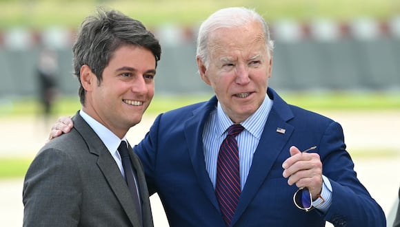 El presidente estadounidense Joe Biden (centro) es recibido por el primer ministro francés, Gabriel Attal, a su llegada al aeropuerto de Orly, cerca de París, el 5 de junio de 2024, mientras viaja para conmemorar el 80.º aniversario del Día D. (Foto de SAÚL LOEB / AFP)