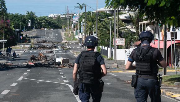 La policía patrulla una calle bloqueada por escombros y artículos quemados tras los disturbios nocturnos en el distrito Magenta de Noumea, territorio francés de Nueva Caledonia en el Pacífico, el 18 de mayo de 2024. (Foto de Delphine Mayeur / AFP)