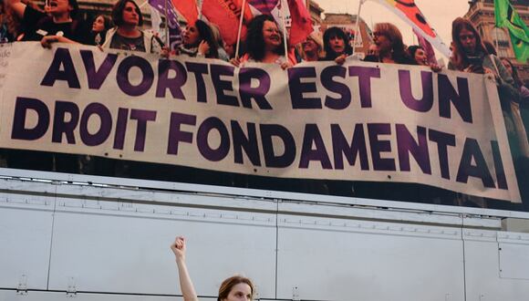 Una mujer aprieta el puño mientras baila frente a una pantalla que muestra un lema que dice "El aborto es un derecho fundamental" en la Place du Trocadero de París, el 4 de marzo de 2024. (Foto de Dimitar DILKOFF / AFP)