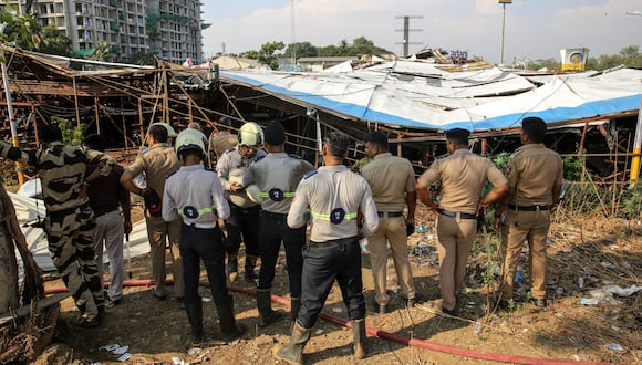 Agentes de policía indios inspeccionan los daños mientras miembros de la Fuerza Nacional de Respuesta a Desastres (NDRF) y otros rescatistas limpian los escombros durante una operación de rescate en el lugar donde un cartel gigante se derrumbó sobre una gasolinera bomba, en Mumbai, India, 14 de mayo de 2024. EFE/EPA/DIVYAKANT SOLANKI