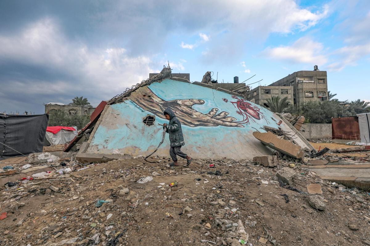 Un niño palestino desplazado interno camina junto a un mural pintado sobre los escombros de una casa dañada en la ciudad de Deir Al Balah, en el centro de la Franja de Gaza, el 2 de diciembre de 2024. (Foto de EFE/EPA/MOHAMMED SABER)