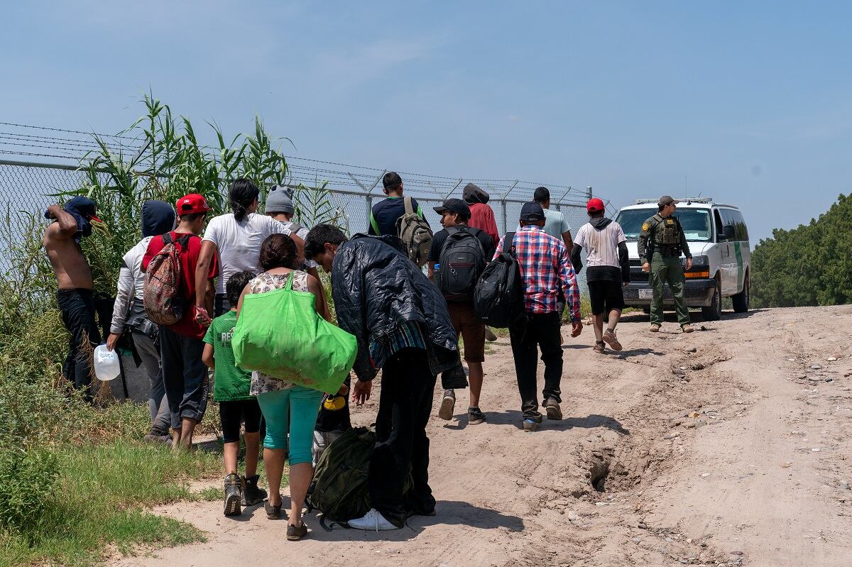 Un grupo de migrantes que cruzaron a Estados Unidos desde México en Eagle Pass, Texas, son liderados por un agente de la Patrulla Fronteriza el 25 de agosto de 2023. (Foto de SUZANNE CORDEIRO / AFP)
