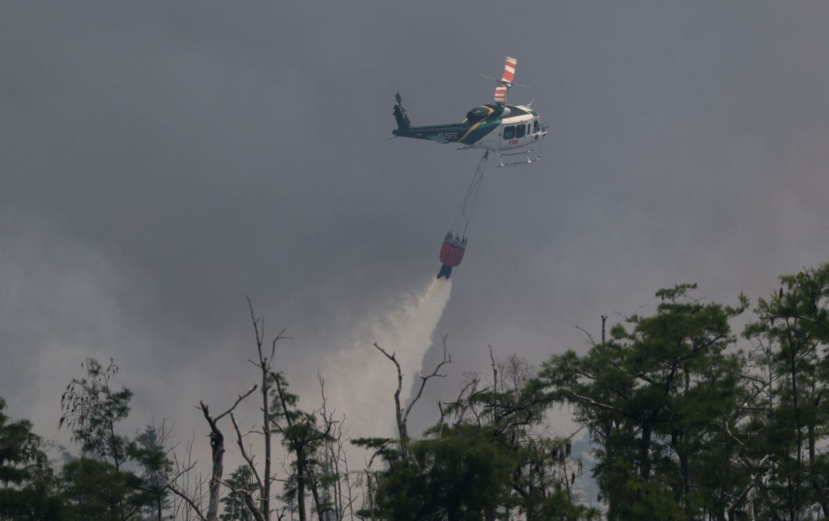 Desde el 1 de enero, casi 2,000 incendios forestales han quemado más de 120,000 acres en Florida. En la imagen, un helicóptero de bomberos del Servicio Forestal de Florida arroja un balde de agua sobre un incendio forestal el 14 de abril de 2026 en Naples, Florida (Foto: Joe Raedle/Getty Images/AFP)