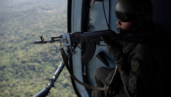Una artillera de un grupo de operaciones especiales sostiene su rifle AK-103 a bordo de un helicóptero MI17, en el estado de Amazonas, en la frontera entre Venezuela, Colombia y Brasil, el 21 de diciembre de 2022. (Foto de Yuri CORTEZ / AFP)