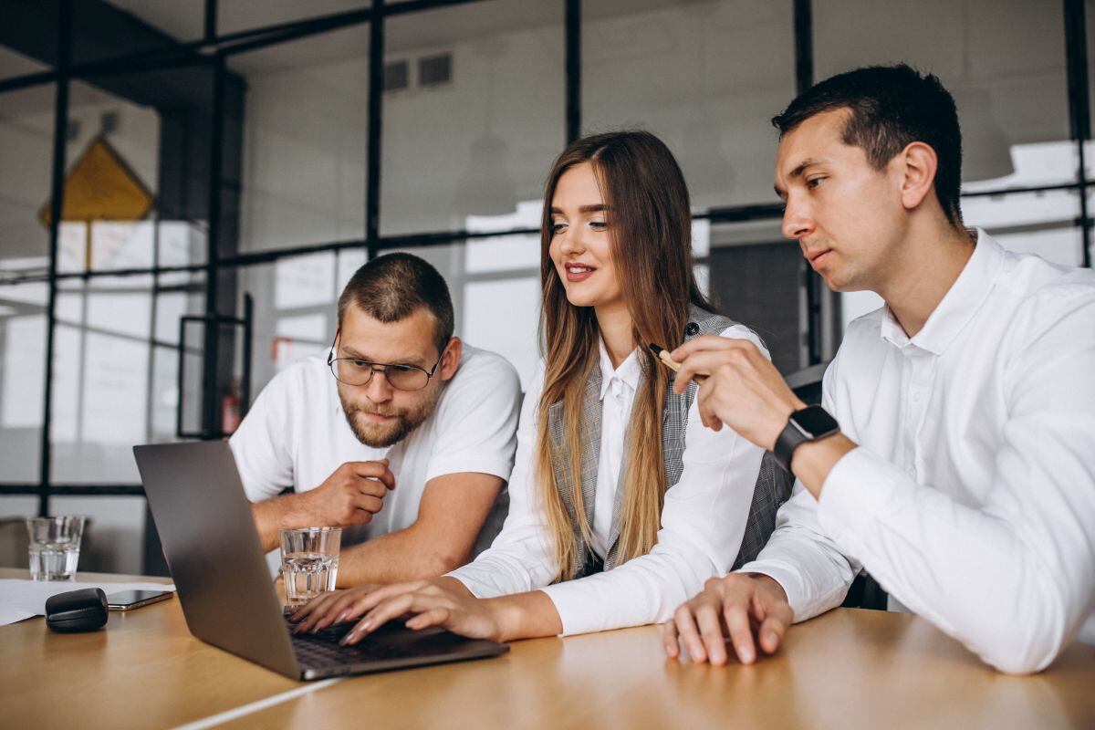 Tres personas en una oficina de trabajo mirando una laptop. (Foto: Freepik)