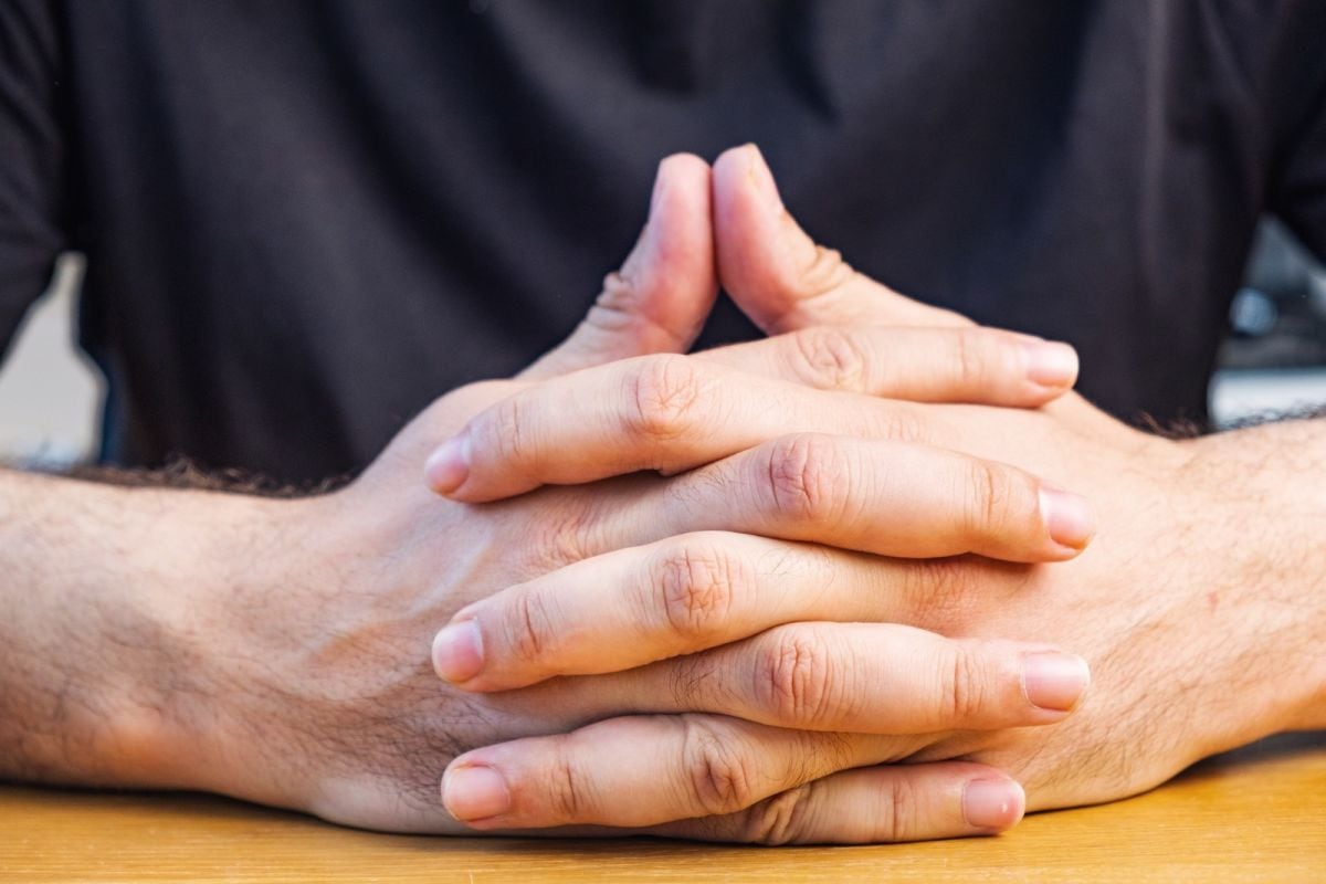 Entrelazar las manos también refleja que la persona está dispuesta a escuchar y a participar de manera activa en la conversación. (Foto: iascic / iStock)