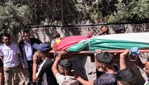 Los dolientes cargan el cuerpo de Ahmad Ramzi Sultan, un palestino de 20 años de origen gazatí que vivía en Ramallah antes del conflicto en la Franja de Gaza entre Israel y Hamás, durante su funeral después de su muerte. (Foto de Zain JAAFAR / AFP)