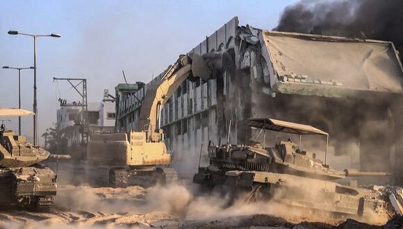 Tanques israelíes rodando mientras una topadora del ejército derriba un edificio en llamas dentro de la Franja de Gaza, el 11 de noviembre de 2023. (Foto de Armada israelí / AFP)