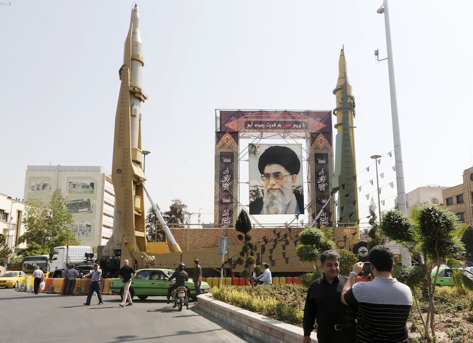 Ciudadanos iraníes pasan junto a los misiles balísticos de alcance medio Sejil (izquierda) y Qadr-H, expuestos al lado de un retrato del líder supremo iraní, el ayatolá Alí Jamenei, el 25 de septiembre de 2017, en la plaza Baharestan de Teherán. (Foto de ATTA KENARE / AFP).
