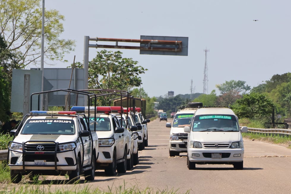 Vehículos transitan por una carretera bajo custodia policial en el municipio de Yapacaní, Santa Cruz, Bolivia, el 25 de agosto de 2026. (Juan Carlos Torrejón / EFE)