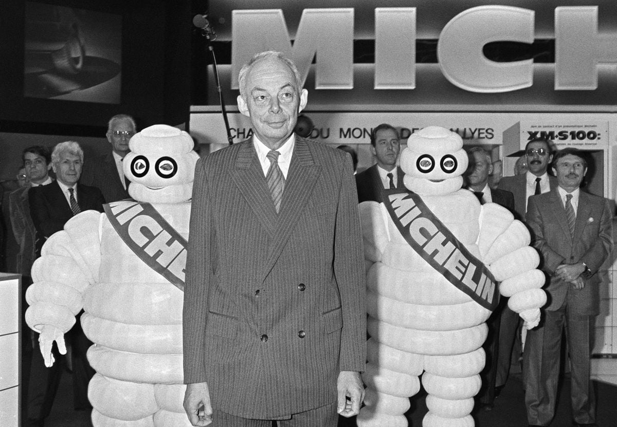 François Michelin, director general del grupo francés de neumáticos, camina, el 5 de octubre de 1984, en el Salón del Automóvil de la Porte de Versailles, en París, rodeado por dos bibendums (Foto: Dominique Faget / AFP)