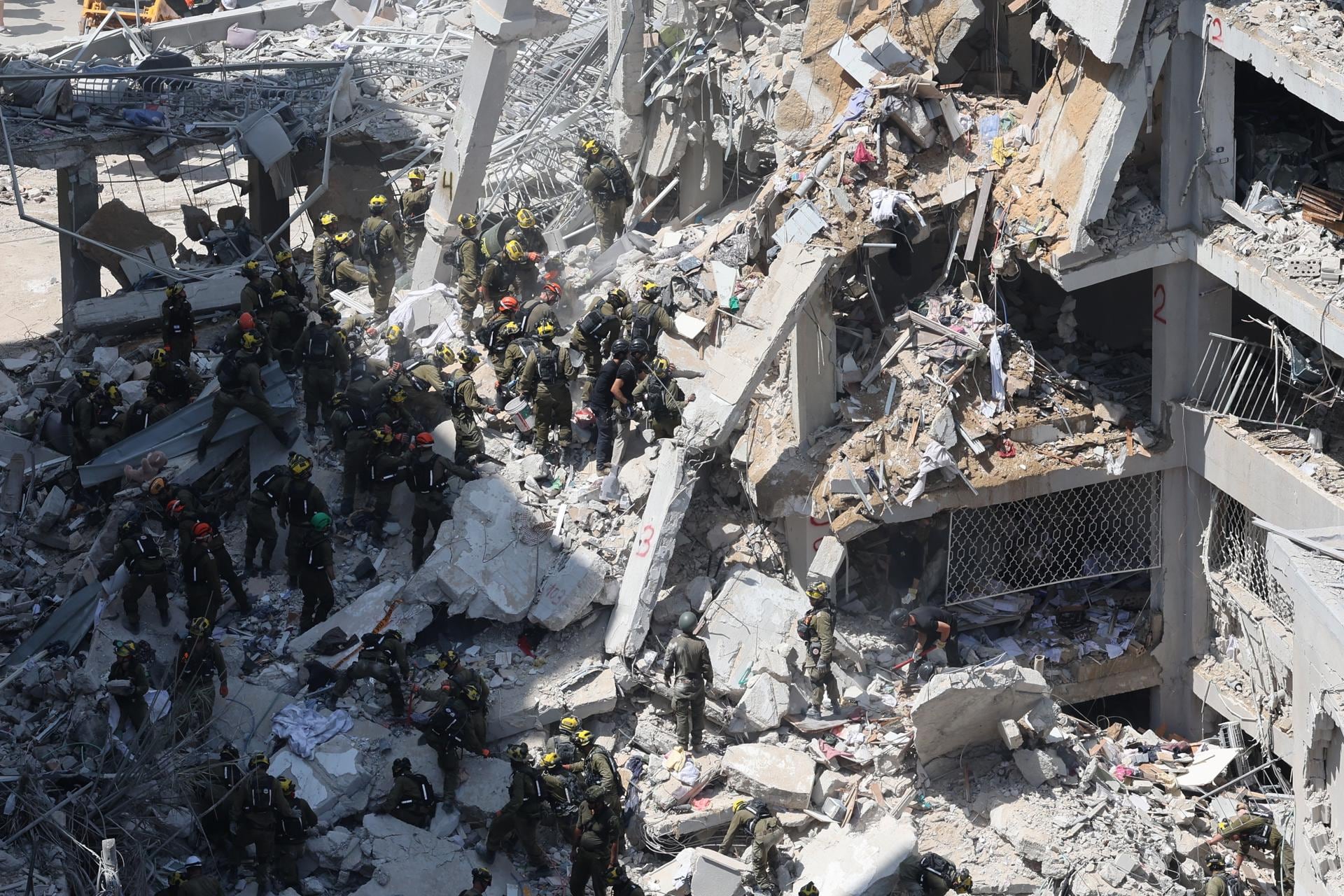 Miembros del Comando del Frente Interior de Israel buscan a personas desaparecidas bajo los escombros de un edificio residencial parcialmente derrumbado en Bat Yam, en el centro de Israel. (EFE/EPA/ABIR SULTAN).