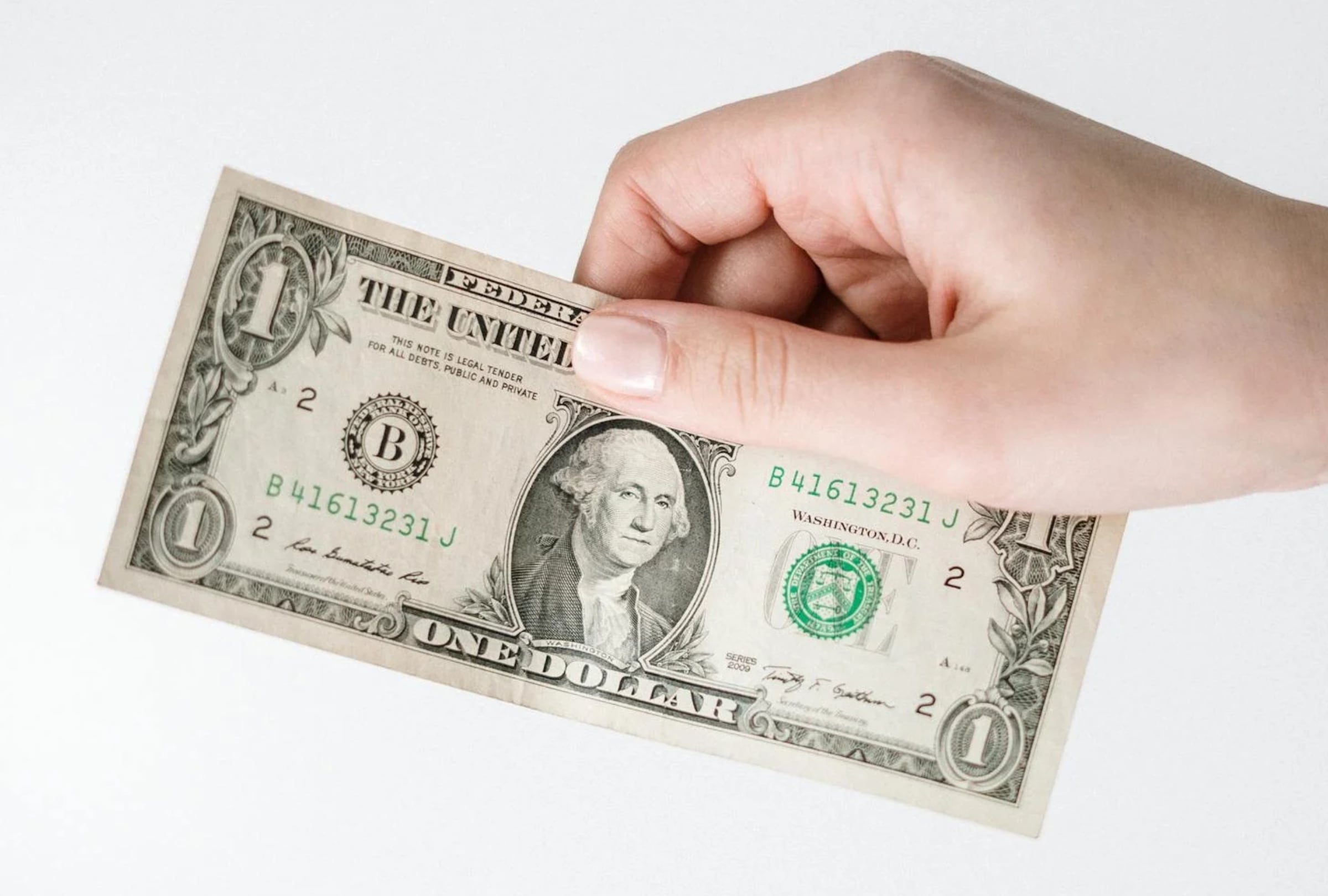 Un ejemplar de 1 dólar sostenido por una persona (Foto: Pexels)