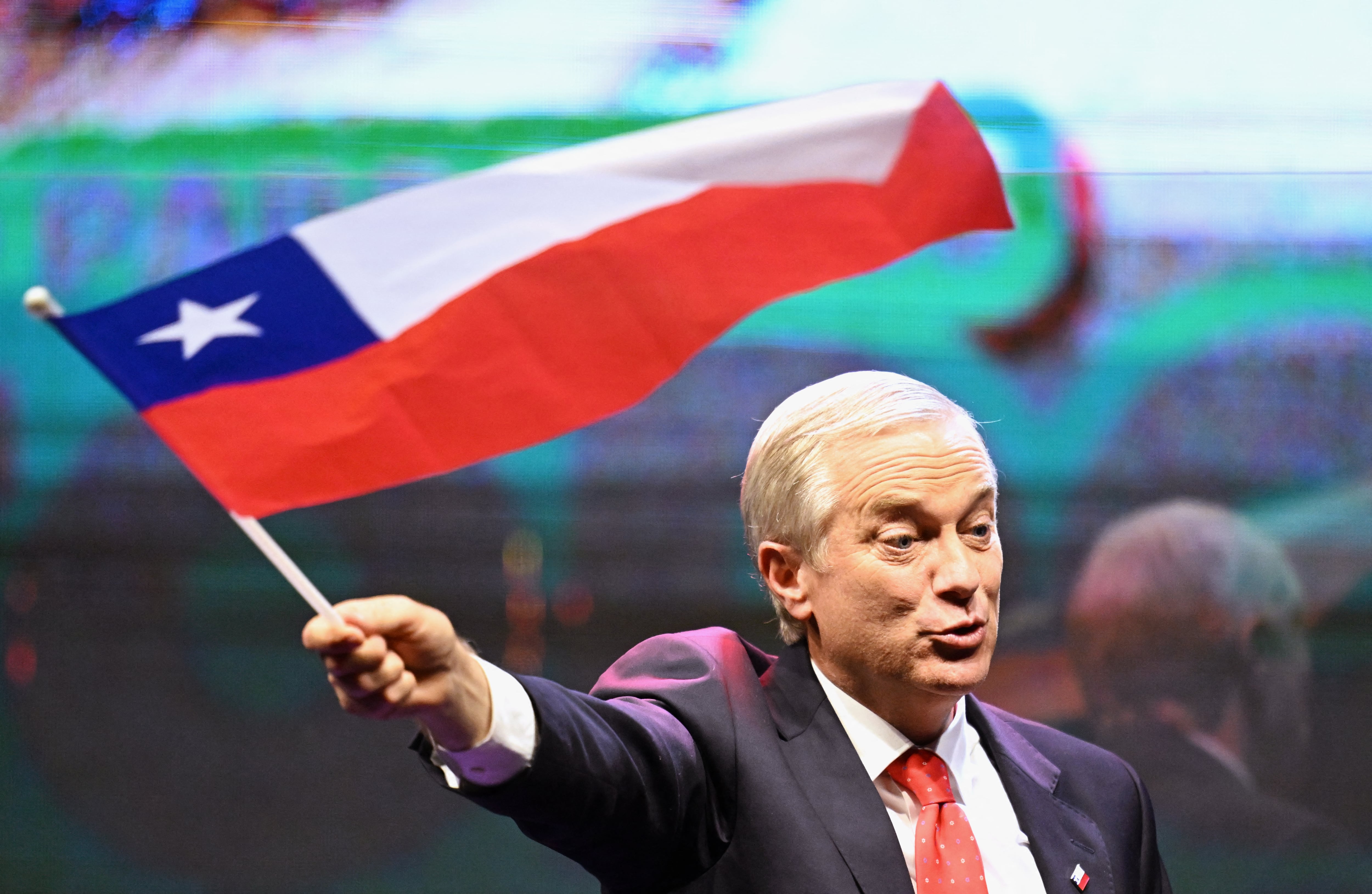El candidato presidencial chileno José Antonio Kast, del Partido Republicano, ondea una bandera de Chile tras los primeros resultados de la primera vuelta. (Foto de Marvin RECINOS / AFP).
