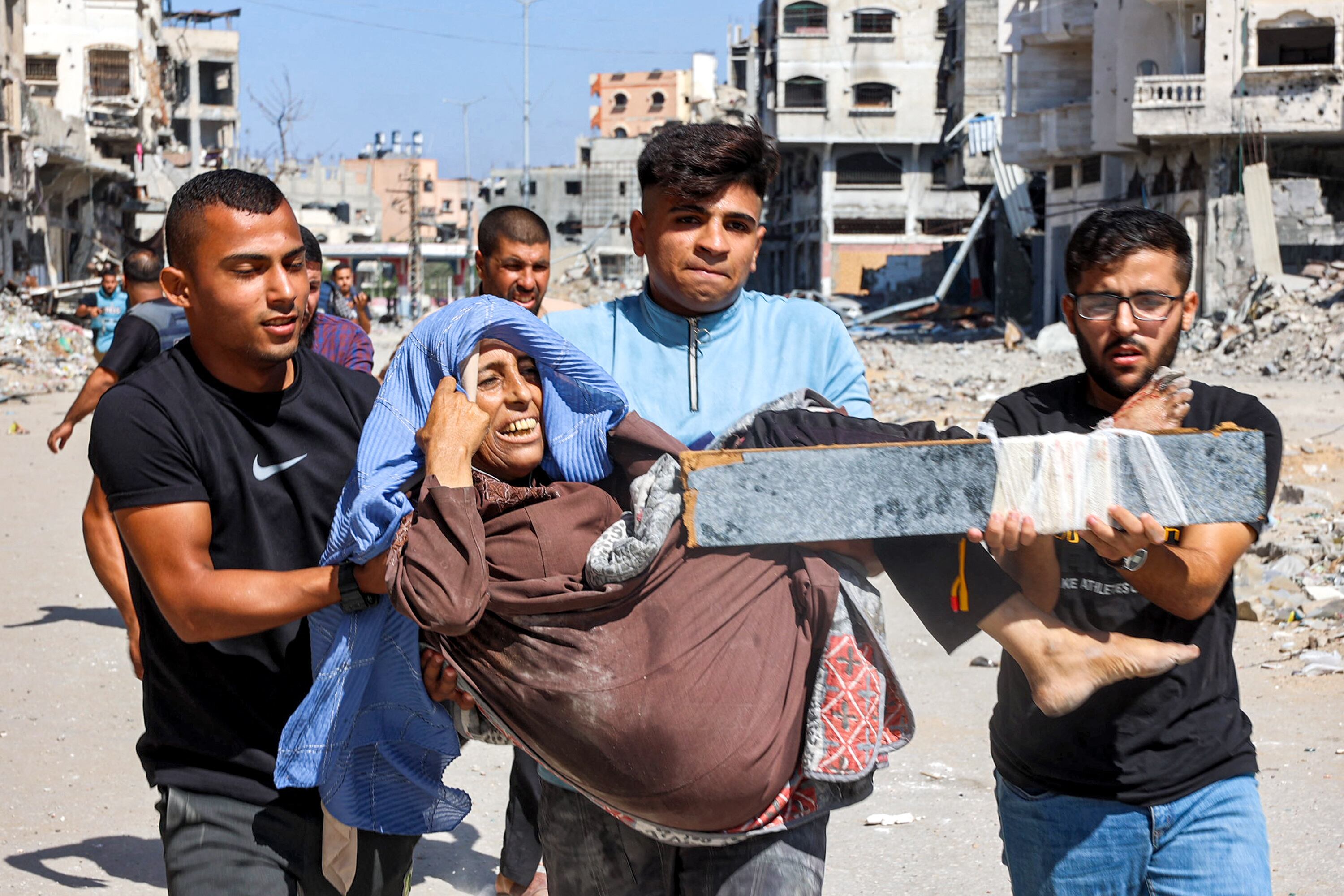 Hombres cargan a una mujer herida para ser evacuada en el campamento de Jabalia para refugiados palestinos, en el norte de la Franja de Gaza, el 9 de octubre de 2024. (Foto de Omar AL-QATTAA / AFP).