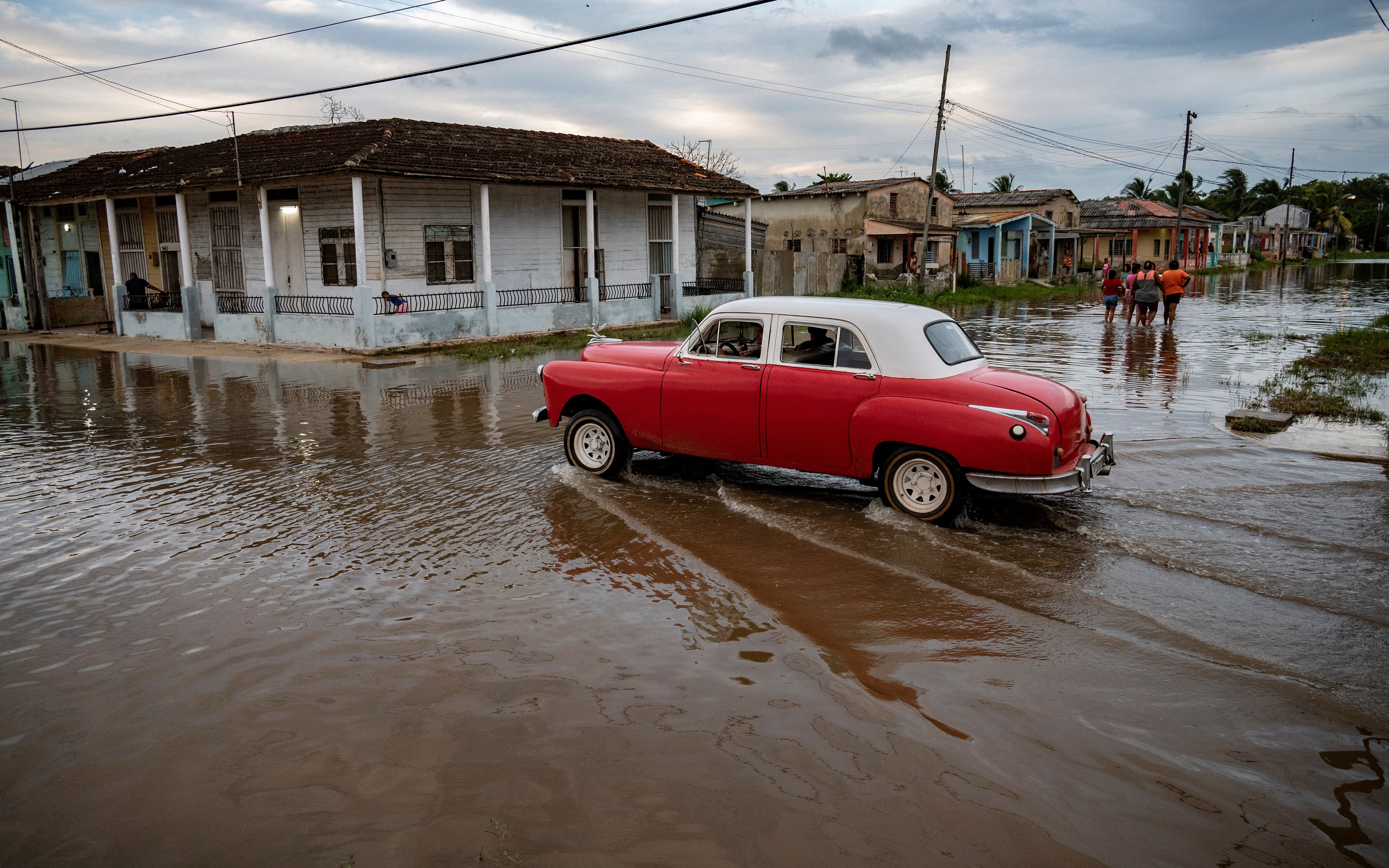 Un viejo automóvil estadounidense pasa por una zona inundada de Batabano, provincia de Mayabeque, Cuba, el 28 de agosto de 2023. (Foto de Yamil LAGE / AFP).