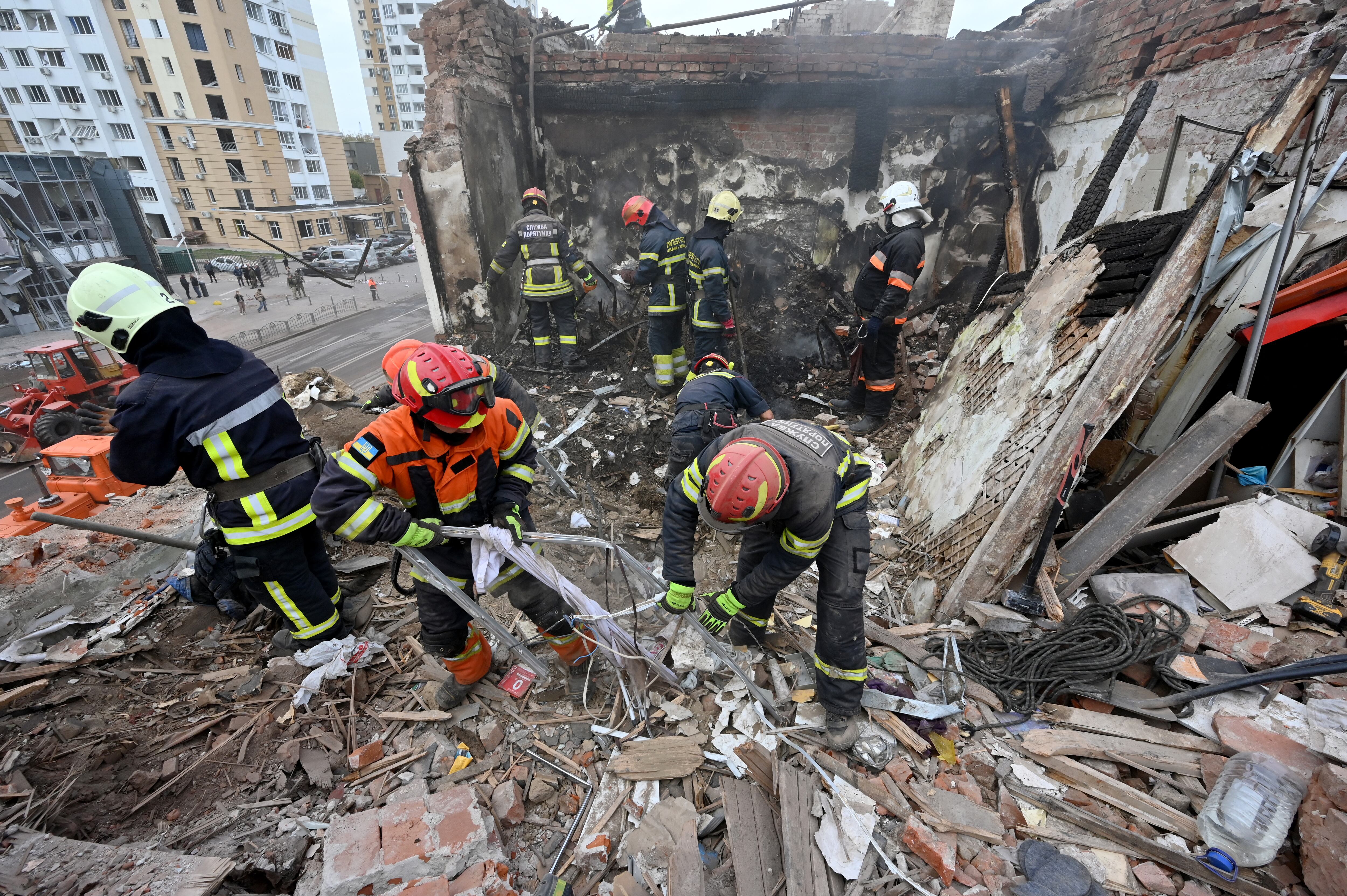 Los rescatistas se encuentran encima de un edificio residencial destruido mientras limpian los escombros tras un ataque con misiles rusos en Járkov el 6 de octubre de 2023, en medio de la invasión rusa en Ucrania. (Foto de SERGEY BOBOK / AFP)